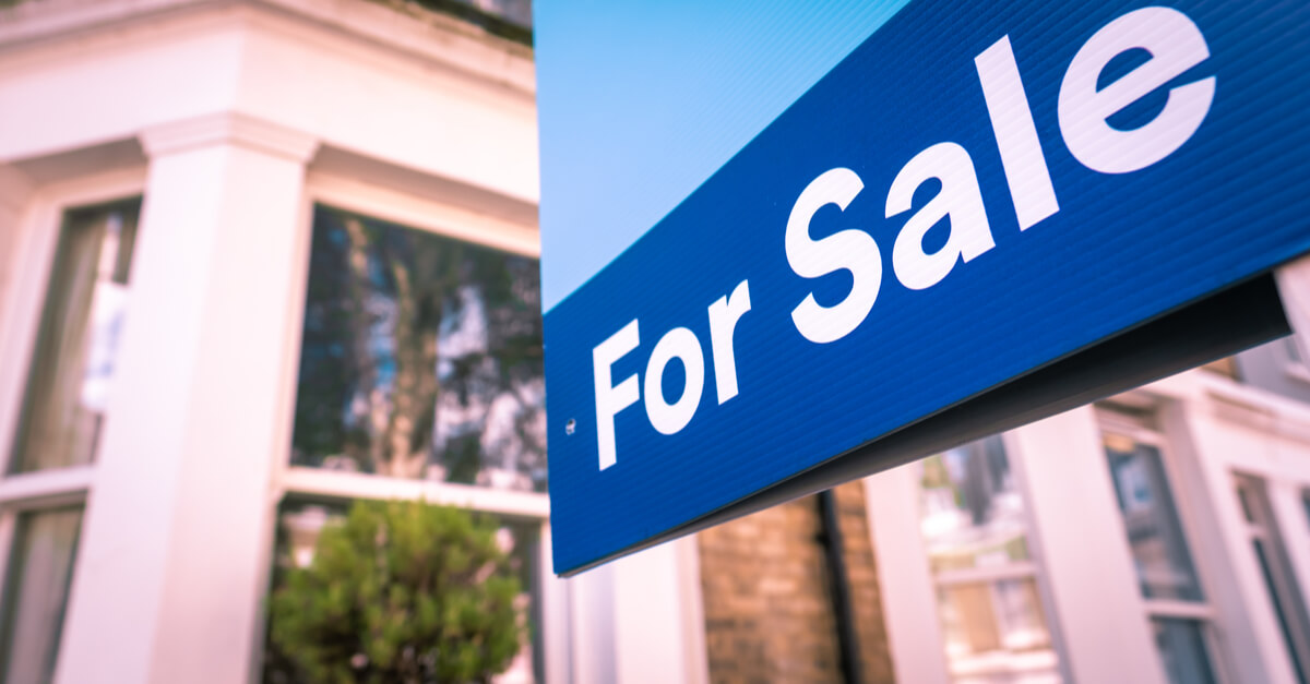 Estate agent For Sale sign on street of houses