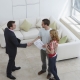 Elevated view of a male real estate agent shaking hands with a man by woman in new home